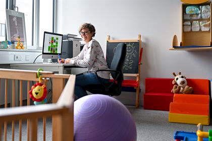 Frau sitzt im Raum für Studierende mit Kind an einem PC